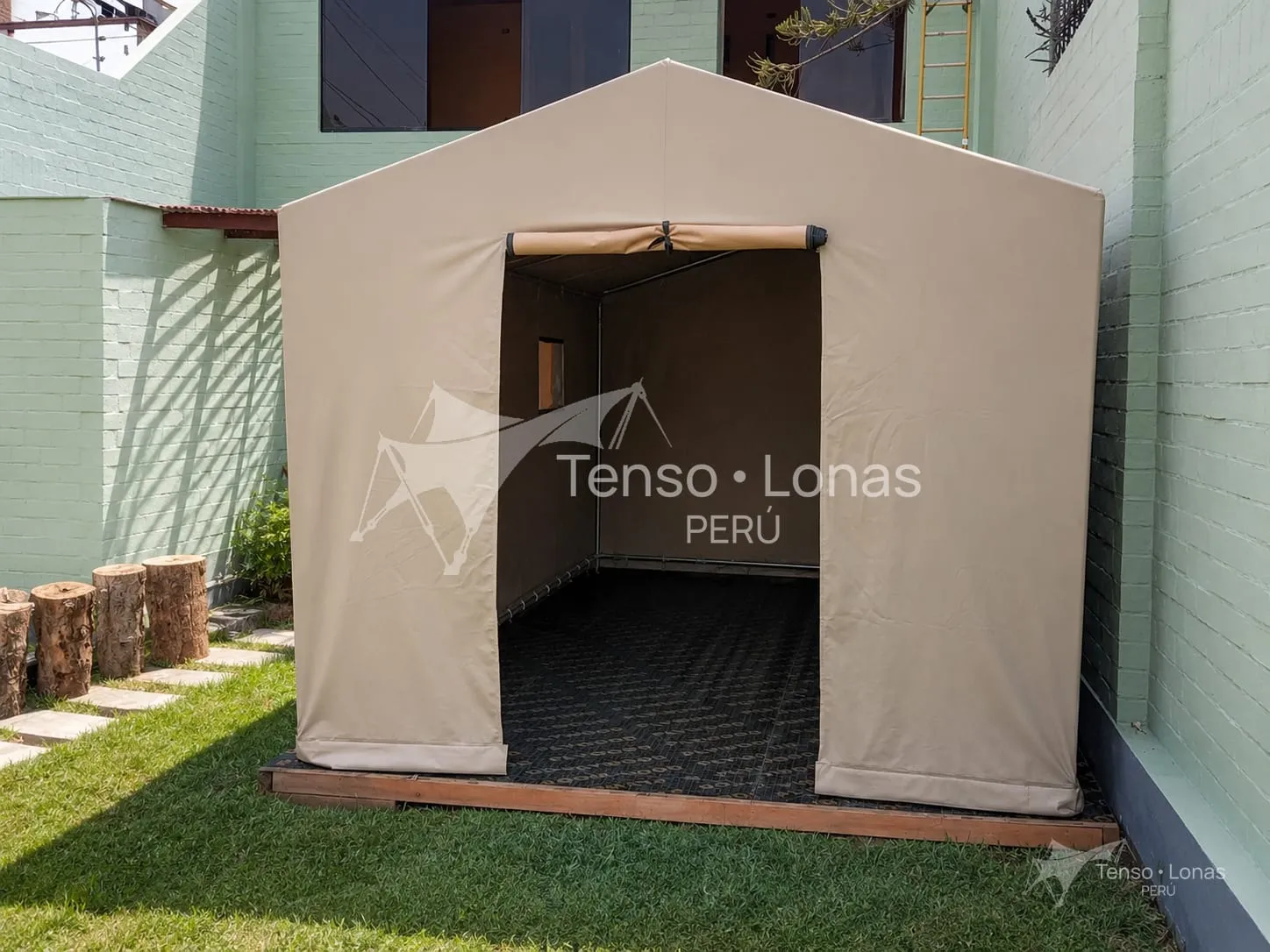 Carpa modelo dos aguas en lona beige con frente abierto, montada sobre plataforma de madera